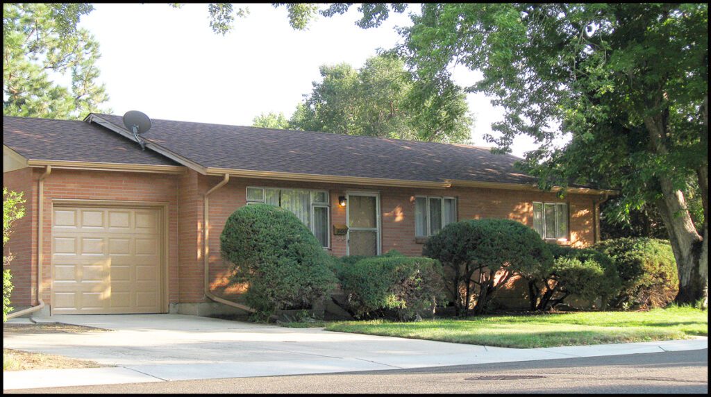 Single-story brick house with green shrubs.